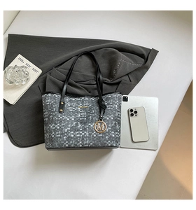 Close-up of a stylish grey checkered tote bag with an M-pendant and golden logo detail