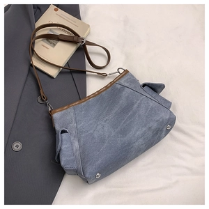 Dettaglio borsa a tracolla in denim azzurro con finiture in pelle marrone e tasche
