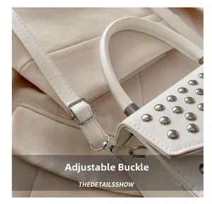 Detail of adjustable metal buckle and strap on white leather bag with silver studs