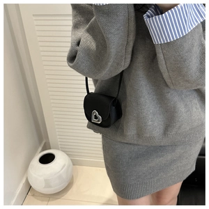Détail du mini sac bandoulière noir avec boucle cœur argentée sur cuir texturé grainé