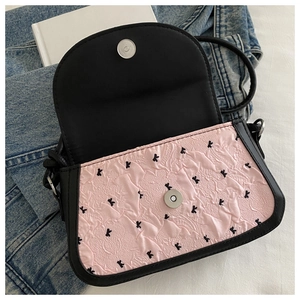 Gros plan du sac à rabat rose texturé avec motif k et boucle magnétique argentée