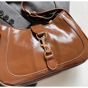 Vue détaillée du sac baguette marron brillant avec une boucle en métal doré