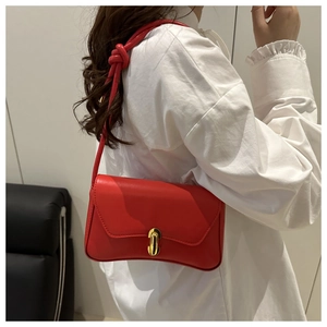 Detailed view of red square bag with gold capsule lock and knot strap detail