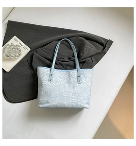 Detail of light blue checkered tote bag with slim shoulder strap and gold rivets hardware