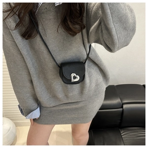 Détail du mini sac bandoulière noir avec boucle cœur argentée et texture cuir grainé