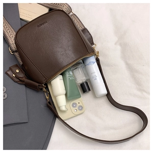 Detail of dark brown retro PU leather bag with woven strap showing daily essentials inside