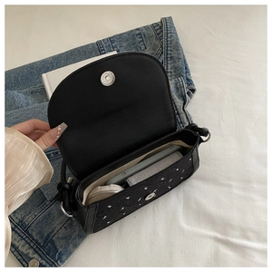 Détail de l'intérieur spacieux du sac noir contenant téléphone et cosmétiques