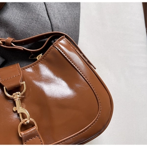 Détail du sac à main marron brillant avec boucle en métal doré et fermeture à glissière