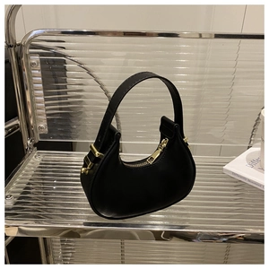 Detail of a black mini hobo bag with gold hardware on a modern acrylic shelf