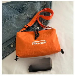 Détail du sac bandoulière en nylon orange texturé avec logo blanc et sangle ajustable