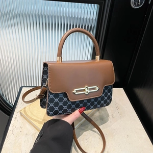 Retro patchwork crossbody bag with brown leather and monogram canvas on a marble surface