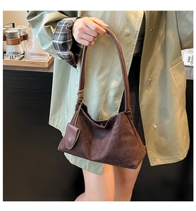 Detail of dark brown suede shoulder bag with leather handle and decorative tassel detail