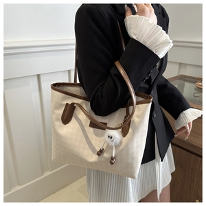 Detail of cream large tote bag with contrast brown trim and cute plush charm pendant
