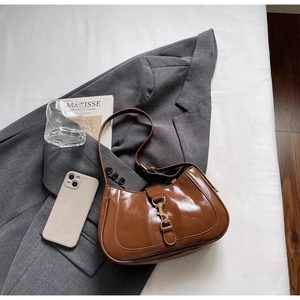 Détail d'un sac sous le bras en cuir verni marron avec un fermoir en métal doré élégant