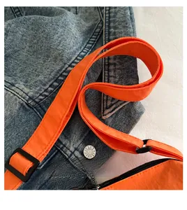 Détail de la bandoulière réglable en nylon et boucle noire d'un sac bandoulière orange