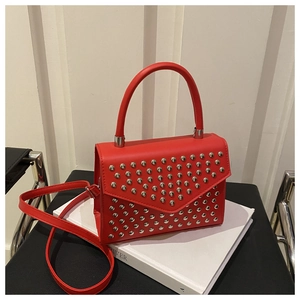 Detailed view of red tote bag featuring silver studs and elegant envelope flap design