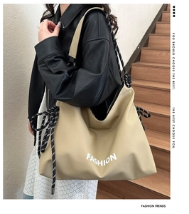 Detail der großen beigen Tragetasche mit FASHION-Aufdruck und gewebtem Seilknotengurt