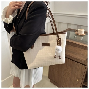 Detail of white canvas tote with houndstooth texture and brown leather trim on a model