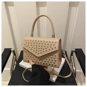 Detail of beige leather crossbody bag with silver rivet studs and top handle