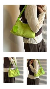 Close-up of vibrant neon green crescent underarm bag with cylindrical strap on model