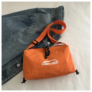 Détail du sac bandoulière en nylon orange avec logo blanc et bandoulière noire ajustable