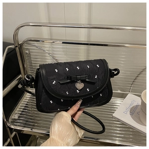 Détail du sac bandoulière noir avec nœud papillon, broderie lapin et breloque en cœur