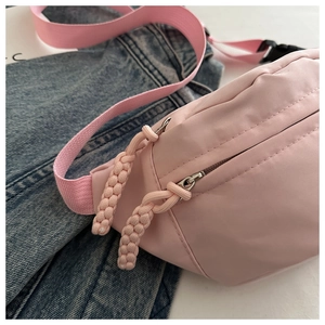 Detailed side view of pink nylon waist bag with woven zipper pulls and buckle strap