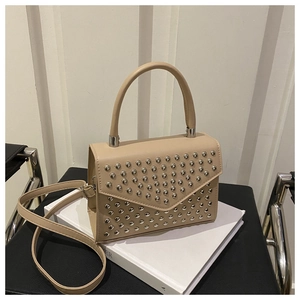 Close-up of beige leather handbag with silver stud accents and flap closure detail