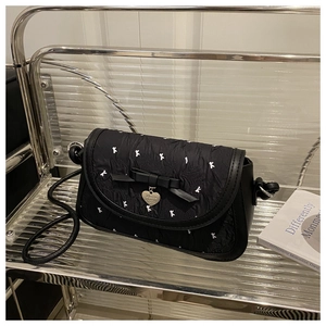 Détail du sac bandoulière plissé noir avec motif K et pendentif en forme de cœur argenté