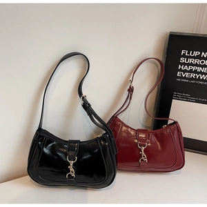Détail de sacs bandoulière en cuir verni noir et bordeaux avec boucles métalliques argentées