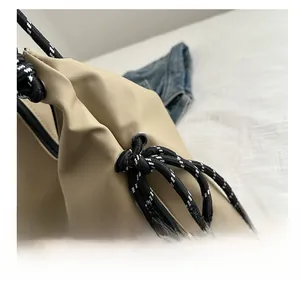 Detail der khakifarbenen Nylontasche mit schwarz-weißem Kordelzug und Metallöse