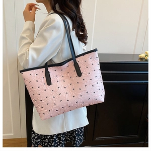 Detail of pink quilted tote bag with black bow pattern and shoulder straps on model