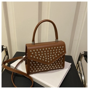 Detail of silver rivets on a caramel brown leather handbag with metallic hardware