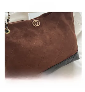 Détail du sac cabas en daim marron matelassé avec bandoulière chaîne dorée et anneaux