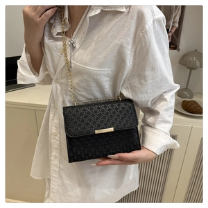 Detail of black woven texture handbag with golden chain strap and metallic buckle