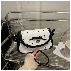 Détail du sac à main plissé blanc avec nœud noir, pendentif cœur et broderies florales