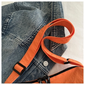 Close-up of orange nylon crossbody bag with adjustable wide strap and textured fabric