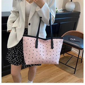 Detailed view of pink pleated tote bag with black bows and thin shoulder straps