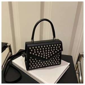 Detail of classic black handbag with silver rivets and polished smooth PU leather finish