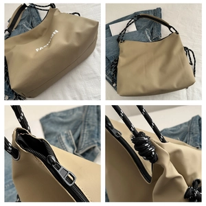 Detail der khakifarbenen Nylontasche mit Fashion-Text und schwarz-weißem Seilgurt
