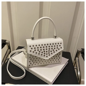 Detail view of white handbag featuring silver metal rivets and a slim shoulder strap