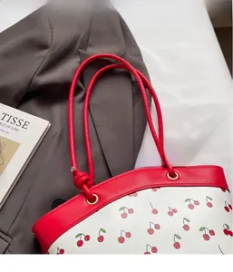 Close-up of cherry pattern print tote bag with vibrant red PU leather handles and metal rings