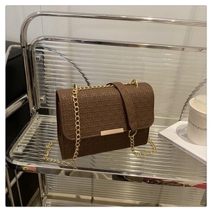 Detail of dark brown leather handbag with geometric M-shaped weave pattern and gold chain