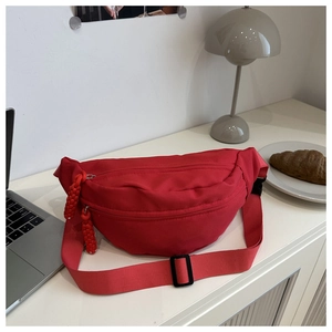 Detail of red crossbody chest bag with hand-woven rope zipper and adjustable buckle strap