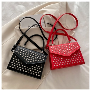 Detail of red and black crossbody bags with round metal rivets on a V-shaped flap