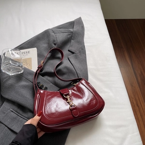 Sac sous le bras rétro en cuir verni bordeaux avec fermoir doré sur blazer gris