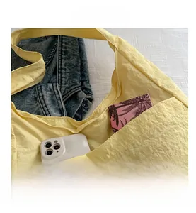 Detail view of large front pocket on beige canvas tote bag storing phone and notebook