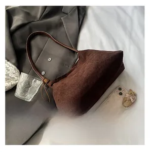 Detail of dark brown suede shoulder bag with smooth leather strap on grey blazer