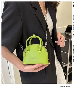 Detail of neon green lychee pattern mini shell bag with silver bead chain and fashion logo