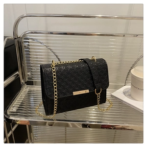 Detail of black woven texture handbag with gold chain strap and metallic rectangular buckle